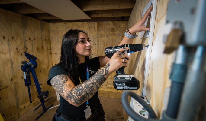 A learner drilling into a wall