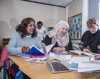 A group of ESOL students (English for speaking of other languages) in the classroom with learning material in front of them