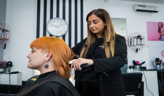 A hairdressing student cutting someone's hair in a salon