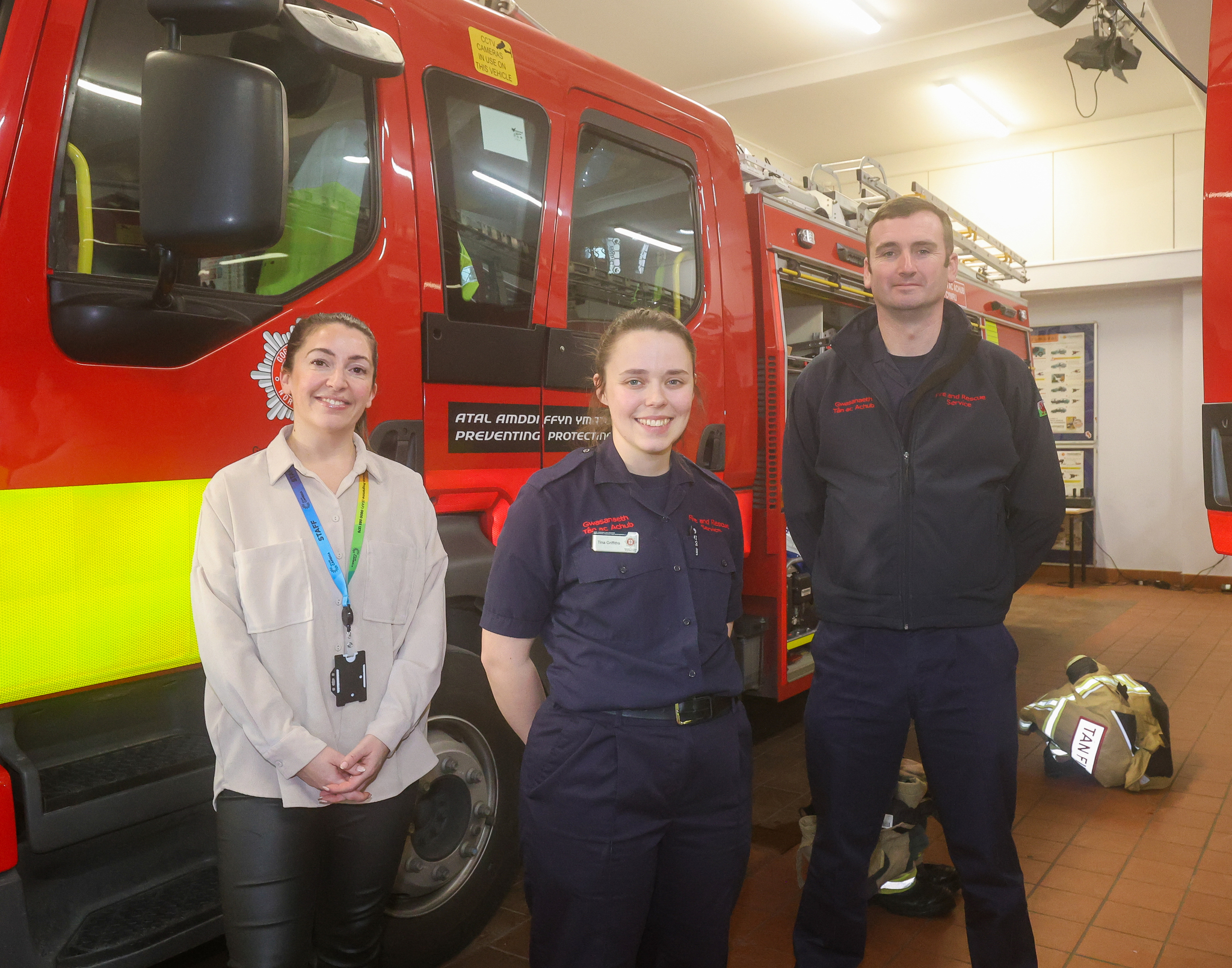 Three people stood in front of a fire truck