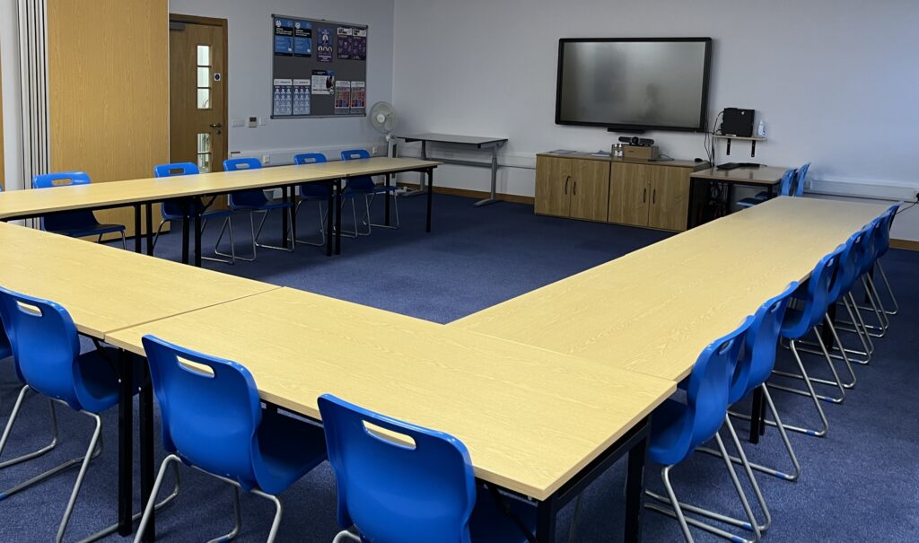 Spacious meeting rooms in Deeside with tables and seats surrounding a TV screen