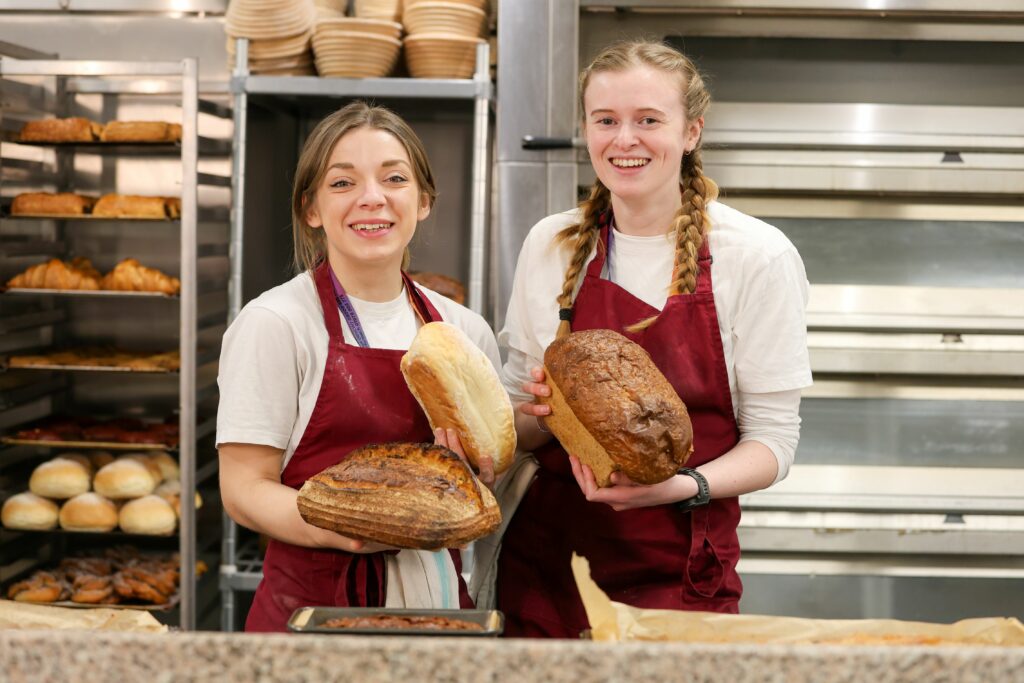 Two Cambria bakers holding loaves of bread for the news story 'The Wales Bakery Conference 2025 comes to Yale'