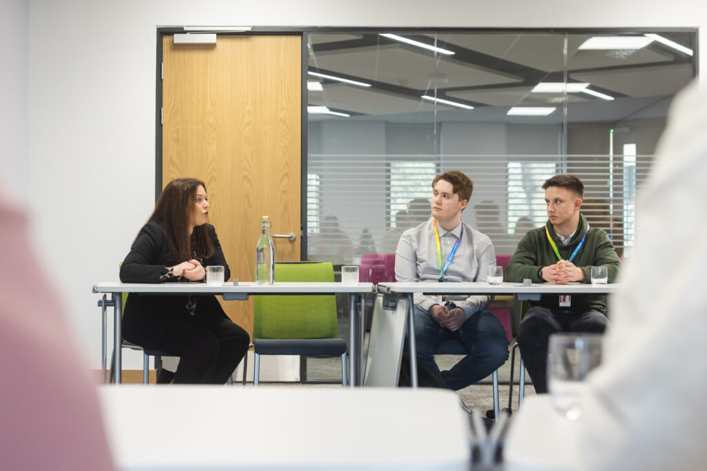 Minster for FE & HE Vikki Howells sat down talking to two students in a boardroom