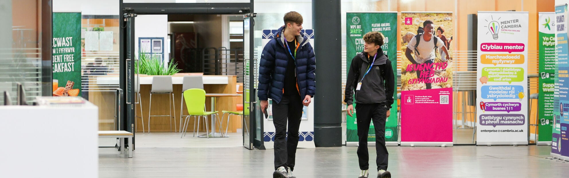 two students walking in Deeside reception area whilst looking at each other