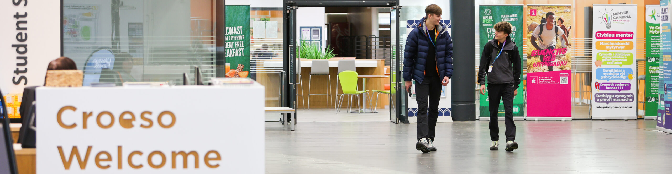 two students walking in Deeside reception area whilst looking at eachother