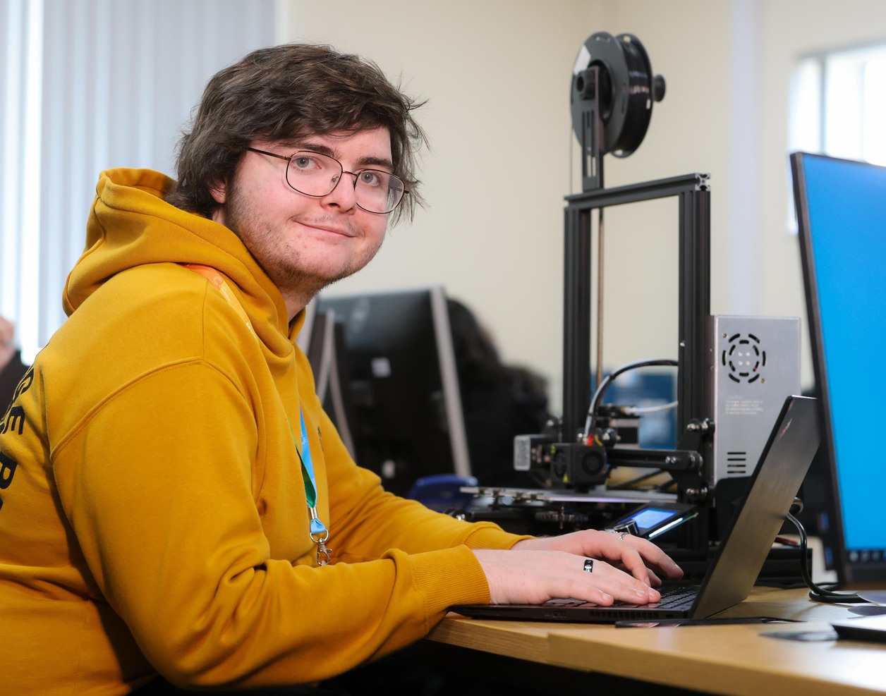 a shot of a learner working on a laptop whilst looking towards the camera