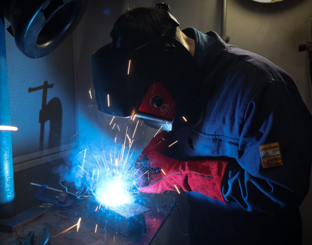 Fab & Weld student welding with sparks flying up