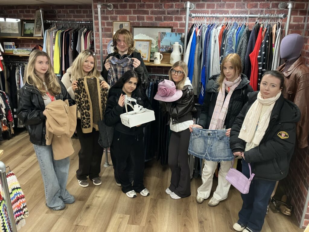 Seven of the 11 students who will run the pop-up shop present some of their favourite finds at Chester’s Hope House store