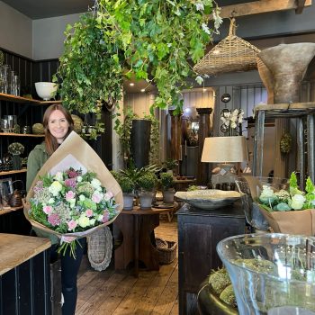 Level 2 & 3 floristry student Emma Howells stood inside a florist with a bouquet in her hands