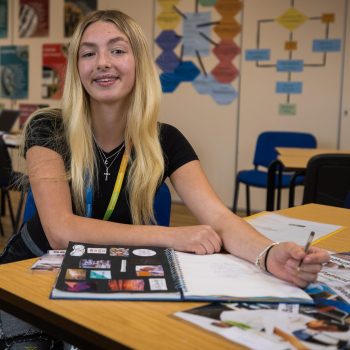 JGW learner Carrieanne Whyborn sat at a desk with a workbook in front of her