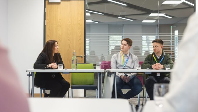 Minster for FE & HE Vikki Howells sat down talking to two students in a boardroom