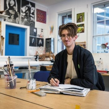 art student Szymon Lewandowski sat down at a table taking a hero shot looking towards the camera