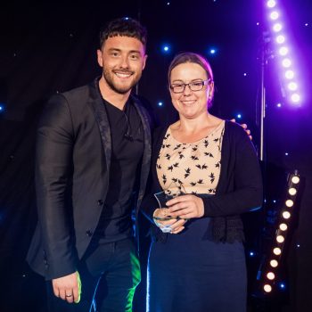 a woman in a light coloured top smiling next to a man at an awards ceremony