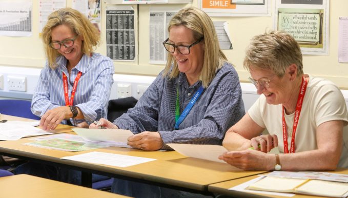 three female adult learners looking at sheets of paper